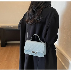 Rear view of a model wearing the quilted mint green crossbody bag with silver chain strap
