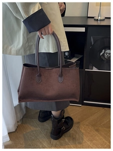 Detail of a dark brown suede tote bag with cylindrical handles for daily commute