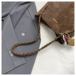 Detail of brown faux suede tote with woven strap and a decorative plush charm