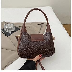 Détail d'un sac à main tressé marron foncé avec ferrures dorées et bandoulière