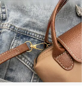 Close-up of golden hardware and contrast stitching on khaki nylon and brown leather bag