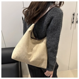 Detailed close-up showing the suede texture and leather strap of this beige tote bag