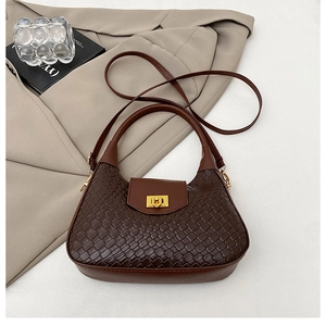 Détail d'un sac à main marron foncé à texture tressée avec une boucle dorée élégante