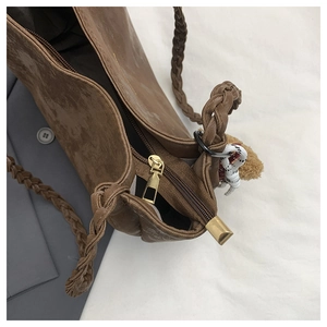 Detail of suede tote bag featuring woven shoulder strap and smooth golden zipper closure