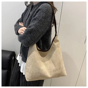 Close-up of minimalist beige suede tote bag showing soft matte texture and leather strap