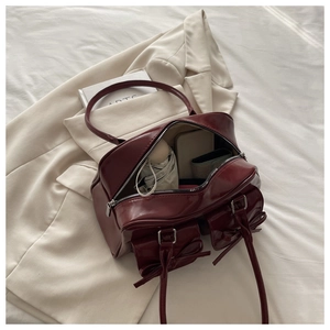 Detail of burgundy glossy shoulder bag showing spacious interior with bow pocket