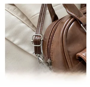 Detail of vintage brown leather bag showing silver metal buckle and strap adjustment