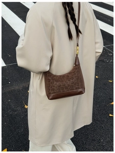 Detail of leopard print suede and brown leather shoulder bag shown in street style scene