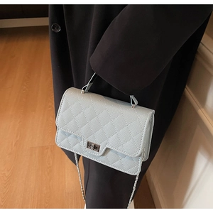Close-up of light blue quilted crossbody bag with silver turn-lock and leather chain strap
