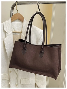 Detail of dark brown faux suede tote bag with long leather straps on a hanger