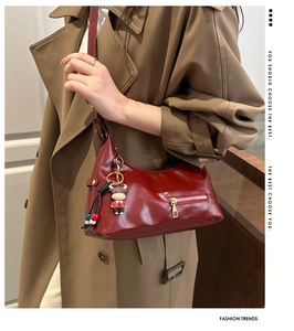Detail of burgundy glossy hobo shoulder bag with zipper pocket and cartoon cow charm
