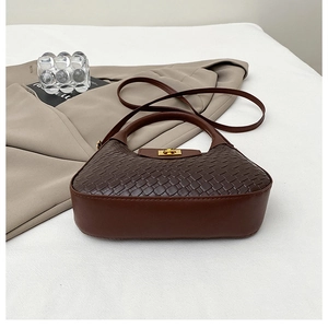 Détail du sac à bandoulière tressé marron foncé avec boucle en métal doré et cuir
