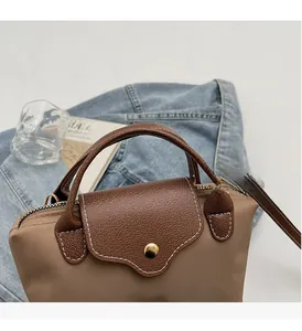 Detail of khaki nylon handbag showing leather flap, metal snap, and adjustable strap