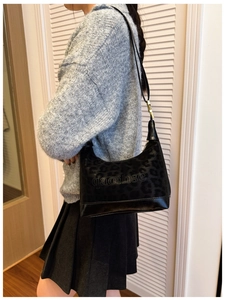 Detail view of black leopard print Hobo bag with letter print shown on a model