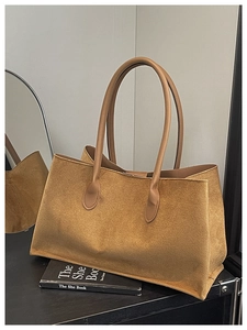 Close-up of caramel suede tote bag with fine texture on a dark wooden surface
