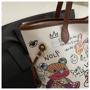 Detail of white lychee leather tote bag with colorful graffiti and brown handle
