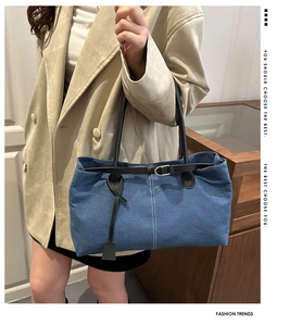 Dettaglio della borsa tote in denim blu con cuciture bianche e cinturino in pelle