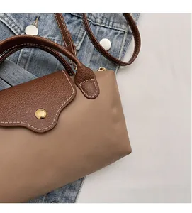 Detail of khaki nylon and brown leather contrast handbag with gold snap closure
