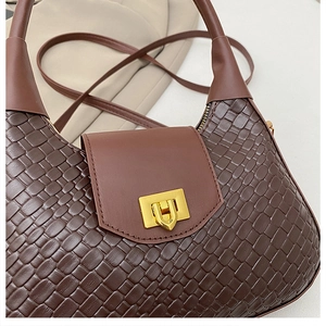 Détail d'un sac en cuir marron tressé avec une boucle en métal doré en forme de U