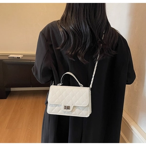 Detailed back view of white quilted crossbody bag with gold-tone twist lock on model