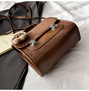 Détail du sac à bandoulière marron vintage avec boucles argentées et ours en peluche léopard