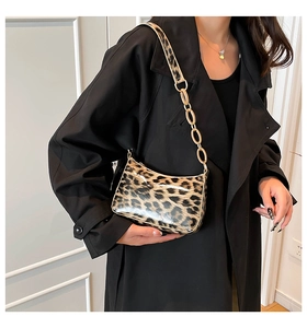 Detail of leopard print underarm bag with glossy finish and gold chunky chain strap