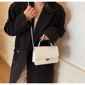 Detailed view of white quilted crossbody bag with metal twist lock and chain strap