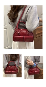 Detail of burgundy leather Boston bag showing front pockets and adjustable shoulder strap