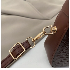 Détail de la quincaillerie dorée et du connecteur de bandoulière en cuir crocodile