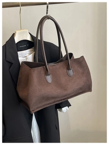 Detail of dark brown suede tote bag styled over a black blazer for a retro look
