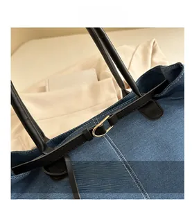 Dettaglio borsa in denim blu con tracolla in pelle nera e fibbia in metallo dorato