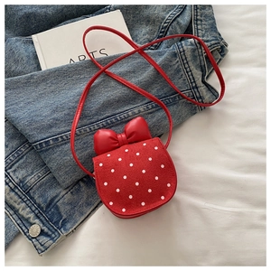 Détail du mini sac bandoulière rouge à pois avec grand nœud sur fond en jean
