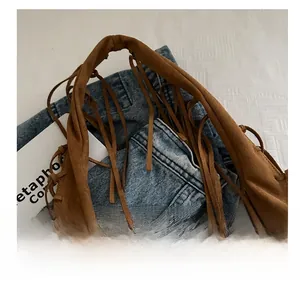 Détail de la poignée du sac en daim marron avec de longues franges décoratives