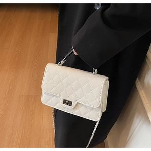 Close-up of beige quilted crossbody bag with metal twist lock and chain strap