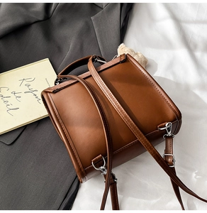 Détail d'un sac à dos en cuir marron avec boucles argentées et pendentif en peluche doux