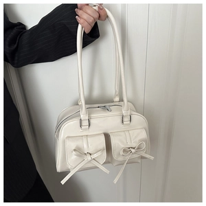 Detail shot of beige patent leather handbag with bow accents and dual flap pockets