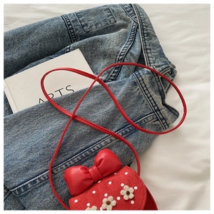 Détail du sac rouge à pois blancs avec fleurs de marguerite et un grand nœud en cuir