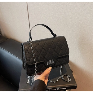 Close-up of black quilted leather handbag with silver turn-lock and chain strap detail