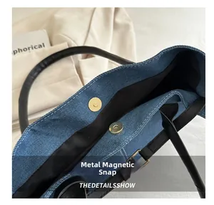 Dettaglio macro della chiusura magnetica dorata e della trama denim di questa borsa tote