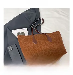 Close-up of brown leopard print tote bag with dark straps on a minimalist bed setting