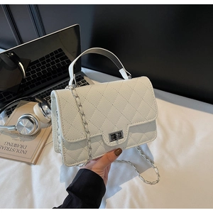Detailed view of white quilted crossbody bag with silver clasp and chain strap