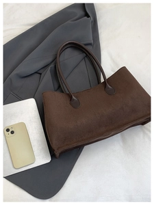 Detail of dark brown suede tote bag featuring rounded leather handles for work
