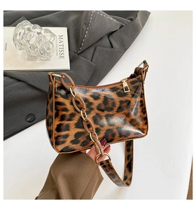Detailed view of leopard print shoulder bag with gold chain and glossy faux leather finish