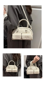 Detail of a creamy white vintage bowling bag with front pockets and silver hardware details