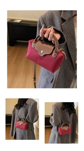Detail of burgundy nylon crossbody bag with brown leather handles and gold snap button