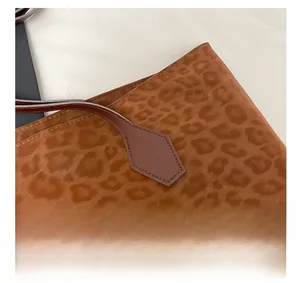 Detailed macro view of leopard print fabric and leather shoulder strap with reinforced stitching
