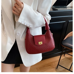 Détail du sac croissant rouge avec texture tressée et boucle dorée porté par un modèle