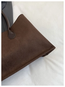 Detailed close-up showing the suede texture and stitching of the dark coffee tote bag