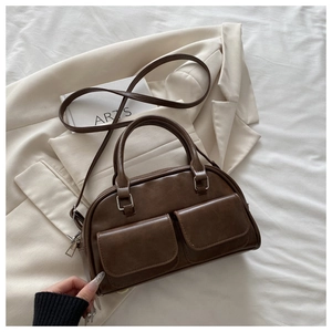 Detail of brown faux leather Boston bag with metal buckles and front pockets
