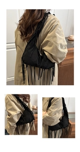 Détail d'un sac cabas en daim noir avec de longues franges et un design épuré à l'épaule